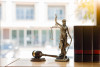 Goddess of justice statue w/scales and gavel on desk by window, arbitration legal case summary