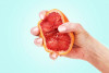 hand squeezing orange or grapefruit