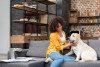 A woman petting a dog on a living room couch